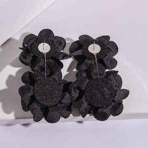 Détails macro des boucles d'oreilles fleurs en tissu noir avec attaches en métal au dos