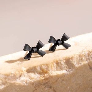 Vue macro de boucles d'oreilles nœud 3D noir mat sur pierre pour style vacances