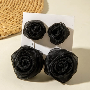Détail de boucles d'oreilles roses en soie noire 3D sur un support en carton blanc