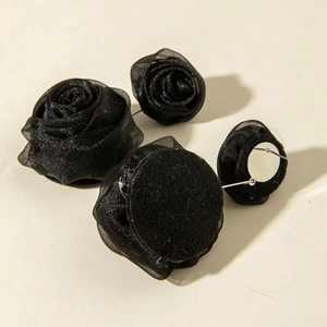 Gros plan de boucles d'oreilles rose en tissu noir avec pétales d'organza superposés