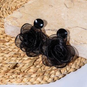 Boucles d'oreilles roses en tissu noir avec pétales de tulle sur fond de pierre minimaliste