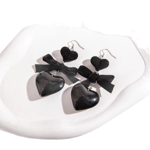 Boucles d'oreilles cœur noir avec nœud en velours style gothique sur plateau blanc