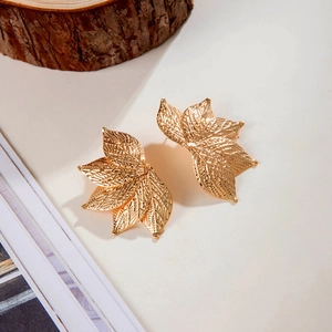 Détail macro de boucles d'oreilles dorées en forme de feuille avec texture nervurée précise