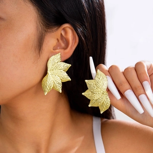 Gros plan de boucles d'oreilles feuilles dorées surdimensionnées avec texture de nervures