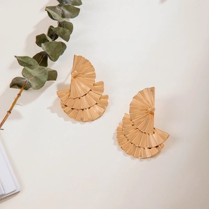 Gros plan de boucles d'oreilles dorées avec texture éventail et plis métalliques fins