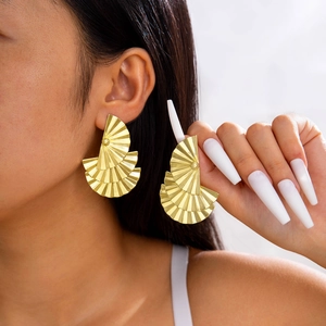Détails macro de boucles d'oreilles dorées en forme d'éventail à texture radiale