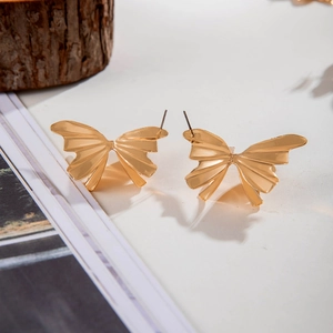 Boucles d'oreilles papillon dorées avec ailes texturées et ombres élégantes portées