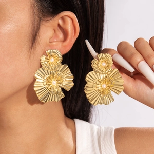 Gros plan d'un mannequin portant de grandes boucles d'oreilles fleurs dorées et perles