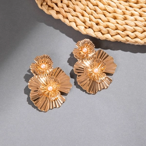 Vue détaillée des boucles d'oreilles fleurs dorées avec pétales plissés et perles