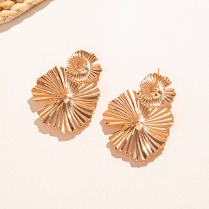 Détail des boucles d'oreilles dorées en forme d'éventail avec texture métallique