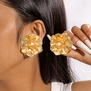 Gros plan de boucles d'oreilles fleurs dorées avec perle portées par un mannequin