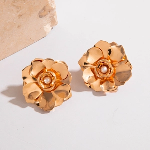 Détail de boucles d'oreilles fleurs dorées multicouches avec perle centrale sur pierre