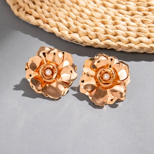 Détail macro d'une boucle d'oreille rose 3D dorée avec perle et pétales ondulés