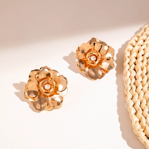 Vue macro de boucles d'oreilles fleur dorée avec texture de pétale et perle blanche