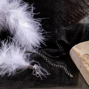 Detailed macro view of white feather choker with silver adjustable clasp and chain link