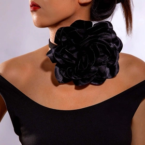 Macro detail of a large black 3D satin flower choker on a soft fabric neck ribbon