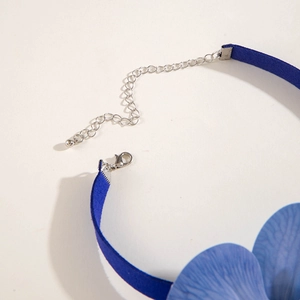 Macro detail of the silver lobster clasp and extension chain on a blue fabric choker
