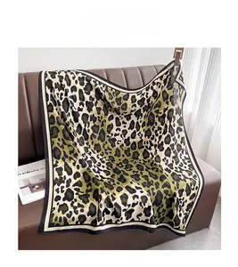 Close-up of leopard print scarf with olive green and black tones on a leather sofa