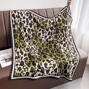 Classic olive leopard print large square scarf draped on a leather sofa for styling