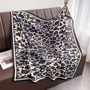 Close-up of classic leopard print scarf on a leather sofa, showing soft fabric detail