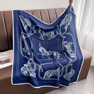Detail eines dunkelblauen Seidenschals mit Pferde-Print auf einem Ledersofa