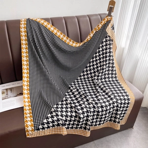 Classic houndstooth print large square shawl with yellow contrast border on leather sofa