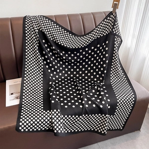 Texture détaillée d'un foulard en soie rétro à pois noirs et blancs sur du cuir
