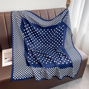 Écharpe en soie à pois bleu marine drapée sur un tabouret en cuir près d'un rideau