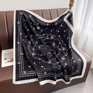 Close-up of square black and white silk scarf with camellia and polka dot patterns