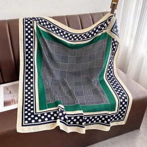 Détail macro d'un foulard en soie avec pied-de-poule vert et bleu, pois et rayures