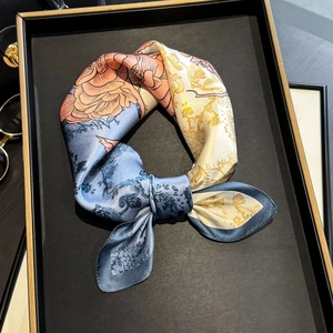Eleganter Seidenschal mit Blumenmuster in Blau und Orange, geknotet auf einem Tablett