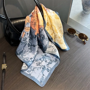 Bedrucktes Seidentuch drapiert auf einer schwarzen Ledertasche mit schicken Accessoires