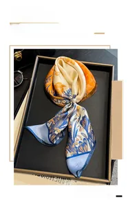 Detail of silk scarf with floral print and pearl buckle on a stylish black tray