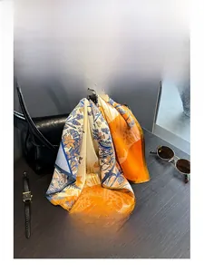 Detail of printed 100% silk scarf with floral patterns tied on a leather handbag