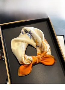 Detailed view of 100% mulberry silk scarf with orange floral prints in an elegant gift box