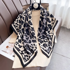 Classic leopard print silk square scarf styled over knitwear on a leather sofa
