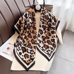 Classic leopard print square scarf draped on a white sweater for a stylish winter look