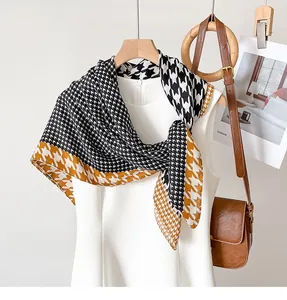 Detail of silk scarf with yellow and black houndstooth pattern draped over white dress