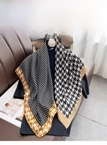 Detail of classic houndstooth silk scarf with yellow border on leather sofa