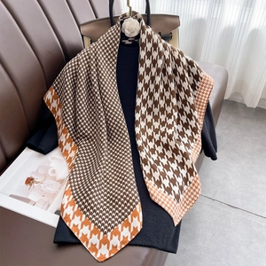 Classic houndstooth print square scarf with orange border draped over a black sweater
