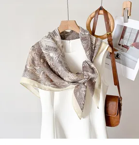 Detail of elegant beige silk scarf with vintage brown tropical prints on a white dress