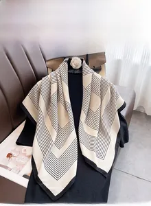 Detail of a large cream square scarf with black geometric stripes draped on a black top