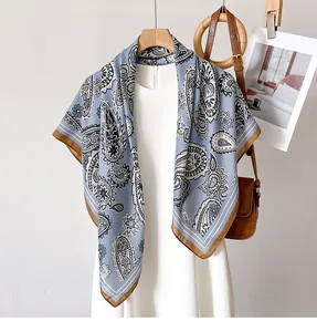 Macro detail of silky light blue paisley scarf with brown borders on a wooden hanger
