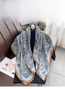 Detailed close-up of intricate paisley print and machine-rolled hem on a blue square scarf
