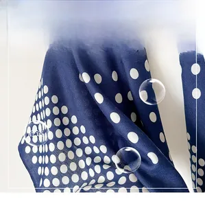 Détail macro d'un foulard en soie bleu marine à pois montrant la texture du tissu sergé