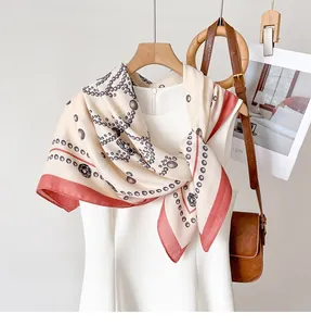 Detail of elegant silk-textured scarf with rose print and pearl patterns on off-white fabric