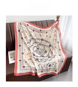 Detail of rose and pearl pattern on a luxury square silk scarf draped on a leather sofa
