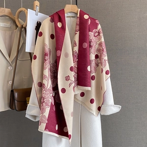 Dettaglio sciarpa floreale bordeaux e beige con frange su un cappotto di lana bianco