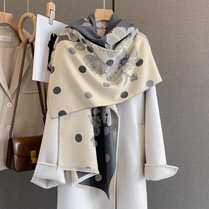 Dettaglio della sciarpa a fiori con frange, abbinata a un cappotto bianco con stile