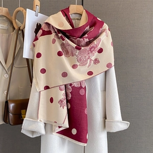 Elegante sciarpa a fiori e pois con bordi a frange su sfondo di cappotto bianco